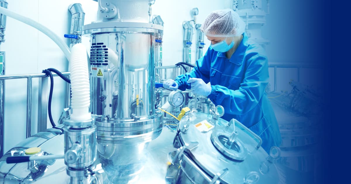 Pharmaceutical factory woman worker in protective clothing operating production line in sterile environment